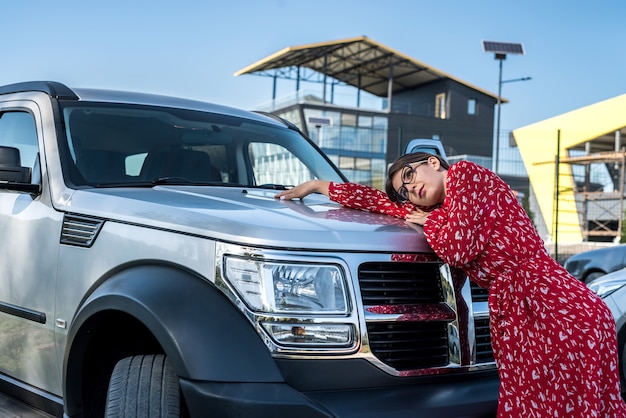 Moda atraente mulher com vestido vermelho de verão em pé perto dela, carro off road, estilo de vida