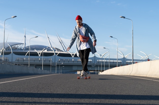 Foto moda callejera y estilo de vida urbano hipster hombre en ropa casual de moda en longboard en la calle de la ciudad