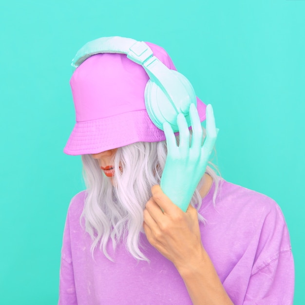 Moda Dj Girl en elegantes auriculares y sombreros de cubo. Tendencias de colores pastel vainilla monocromáticos mínimos