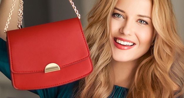 Moda e acessórios mulher bonita feliz segurando pequena bolsa vermelha com detalhes dourados como acessório elegante e compras de luxo