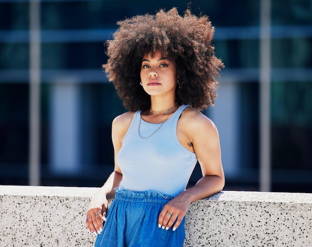 Moda e atitude de retrato com uma mulher negra na cidade ao ar livre em uma ponte durante um dia de verão Estilo de rua ou urbano e uma jovem atraente posando do lado de fora com um penteado afro