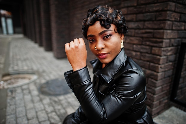 Moda hermosa mujer afroamericana posando en chaqueta de cuero negro en la calle