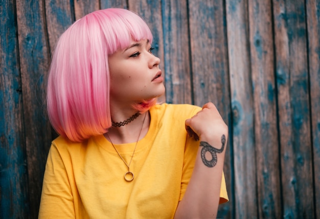 Foto moda hipster asiático de pie junto a la pared de madera en mal estado