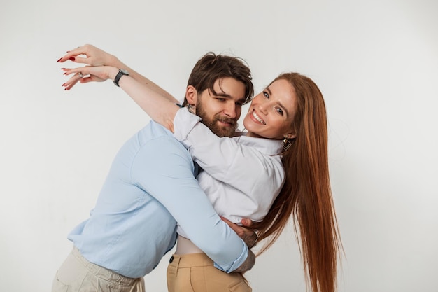 Moda hipster hombre guapo y felicidad hermosa mujer con pelirroja en elegante ropa elegante abrazo y divirtiéndose sobre un fondo blanco Pareja de jóvenes amantes de moda