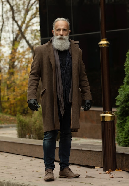 Moda hombre senior con canas y barba está al aire libre en la calle.