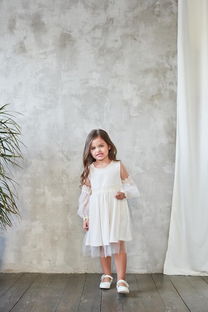 Moda infantil. menina elegante em um vestido branco.