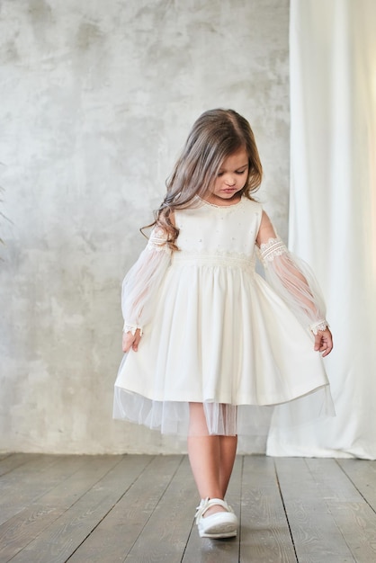 Moda infantil. Niña con estilo en vestido blanco.