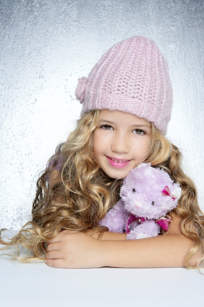 Moda de invierno tapa niña abrazo oso de peluche sonriendo