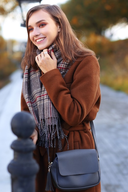 Moda jovem ao ar livre vestindo casaco, cachecol e bolsa