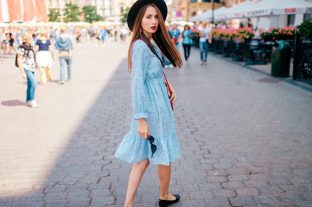 Moda jovem em vestido azul, olhando para trás na rua