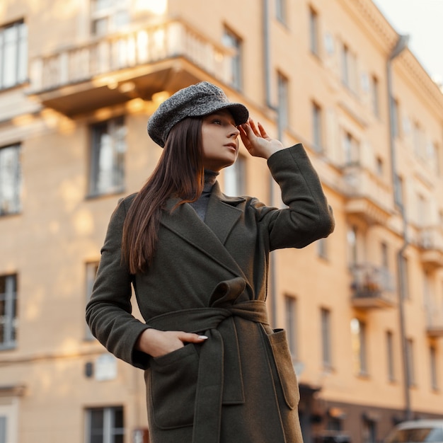 Moda jovem europeia com um chapéu estiloso e um casaco vintage na moda, andando na rua da cidade