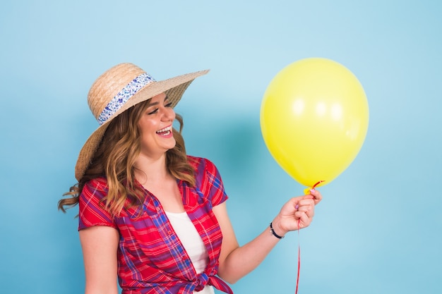 Moda jovem sorridente com balão de ar amarelo sobre fundo azul colorido. conceito de pessoas, feriados e felicidade.