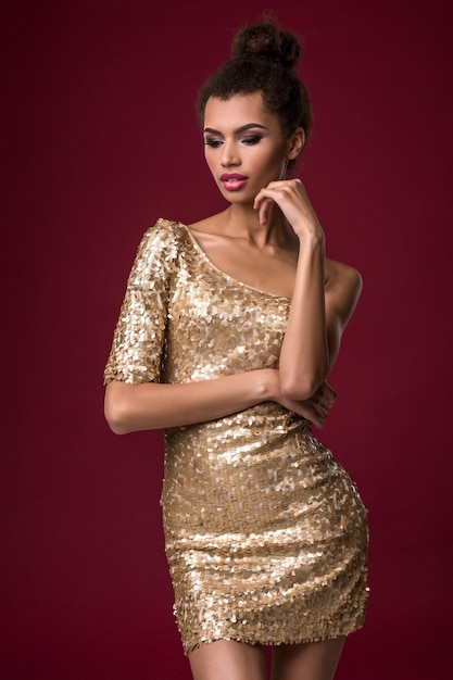 Foto moda joven africana con maquillaje en vestido corto sexy dorado