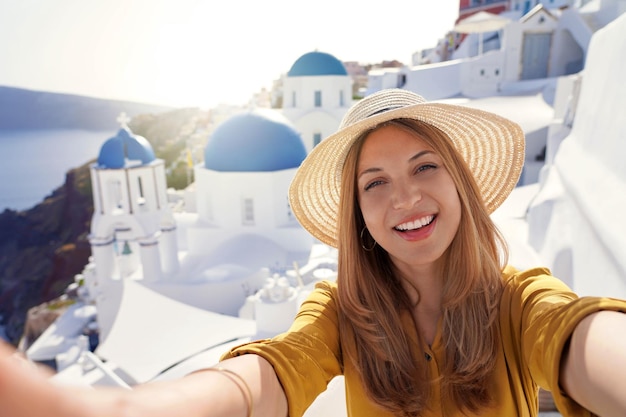 Moda joven brasileña mujer tomando autorretrato al atardecer en la isla de Santorini Grecia