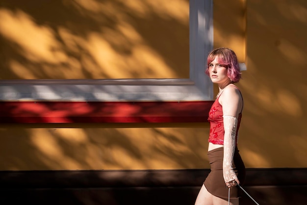 Foto moda joven creativa cabello de color rosa caminando solo en la calle luces y sombras