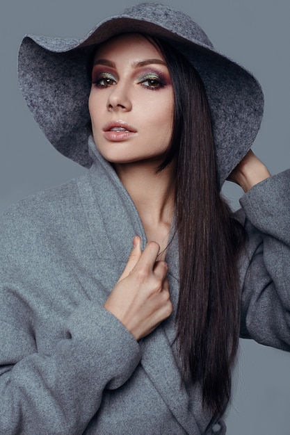 Moda joven mujer morena belleza en abrigo gris y sombrero