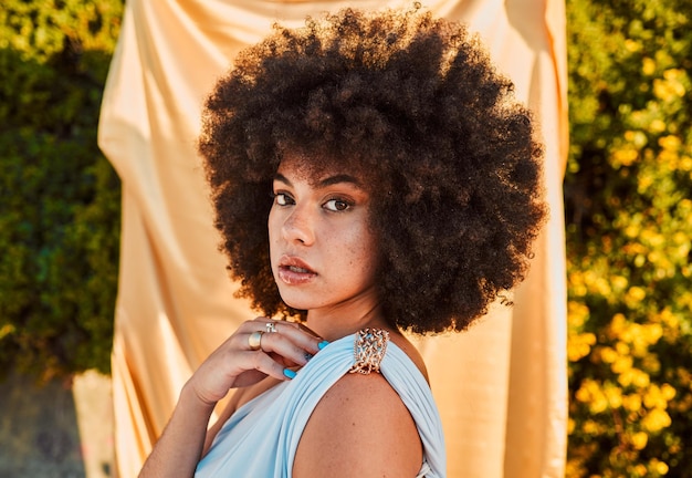 Moda de lujo en el jardín y retrato de mujer negra con fondo de arbusto y plantas en el sol de verano Elegancia belleza y maquillaje orgullosa mujer africana sexy con afro en la naturaleza y tela en el fondo