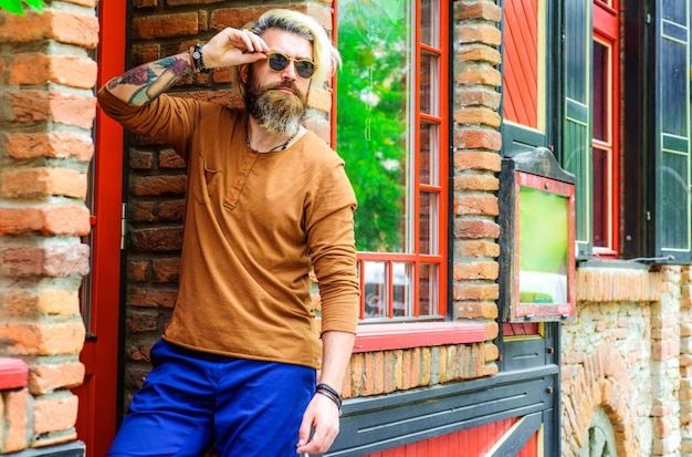 Moda masculina. Hombre guapo con estilo en gafas de sol. Hipster barbudo con gafas.