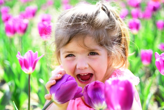 Moda menina verão Infância feliz Primavera tulipas previsão do tempo Criança pequena Beleza natural Dia das crianças Menina no rosto ensolarado da primavera e alergia a flores tão feliz