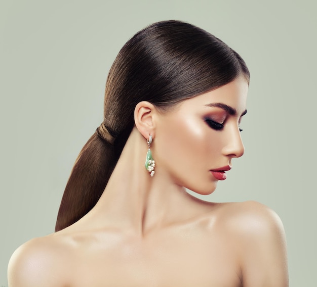 Moda modelo mujer con maquillaje cabello sano y aretes con joyas perlas y gema verde