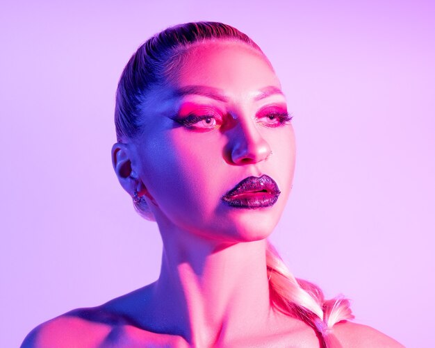 Moda modelo mulher com maquiagem brilhante e luzes coloridas de neon uv posando no estúdio