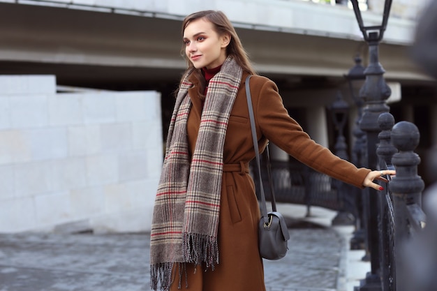 Moda mujer joven al aire libre con abrigo, bufanda y bolso