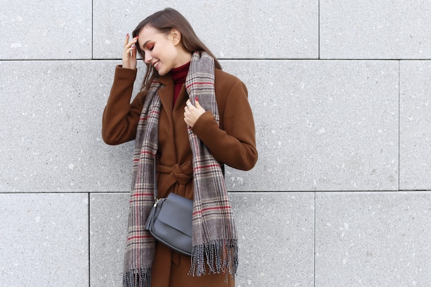 Moda mujer joven al aire libre con abrigo, bufanda y bolso