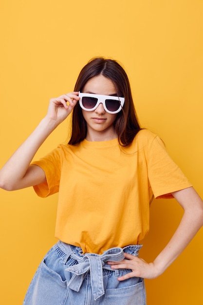 Moda de mujer joven en camiseta amarilla pantalones cortos de mezclilla fondo amarillo