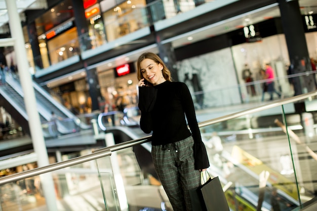 Moda mujer joven de compras en el centro comercial y el uso de teléfono móvil