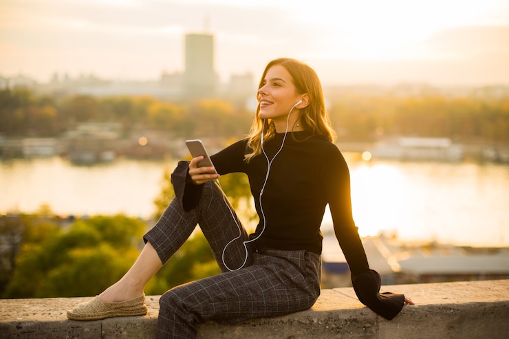Foto moda mujer joven escuchando música desde el teléfono inteligente al aire libre al atardecer