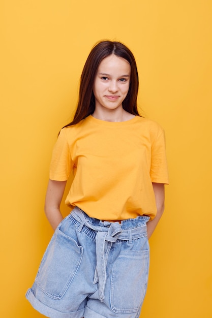 Moda de mujer joven optimista en camiseta amarilla pantalones cortos de mezclilla estilo de vida inalterado