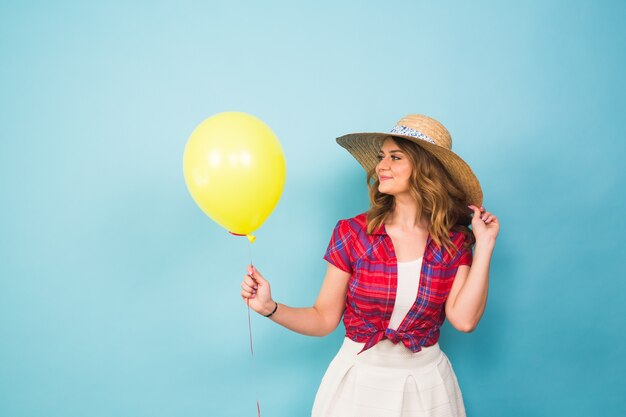 Moda mujer joven sonriente con globo de aire amarillo sobre fondo azul colorido con copyspace.