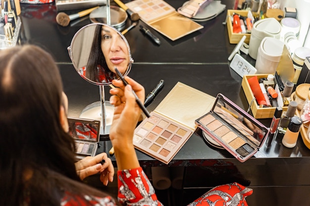 Moda mujer morena preparándose para el evento de fiesta en casa maquillaje de vestuario frente al espejo