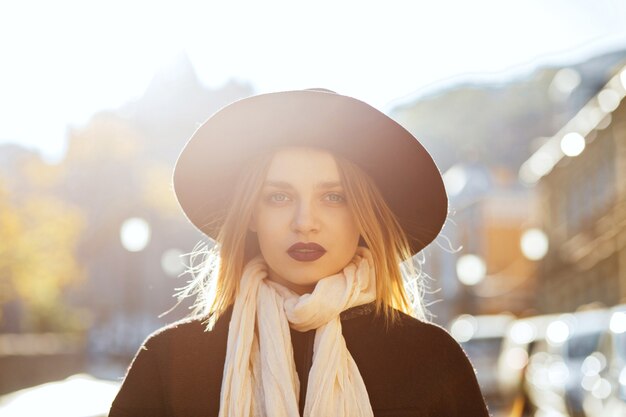 Moda mujer rubia posando en la calle en rayos de sol