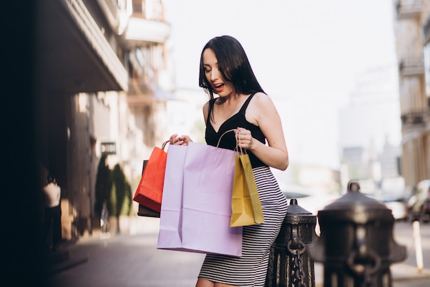 Moda mujer vestida con bolsas de colores en las calles, concepto de compras
