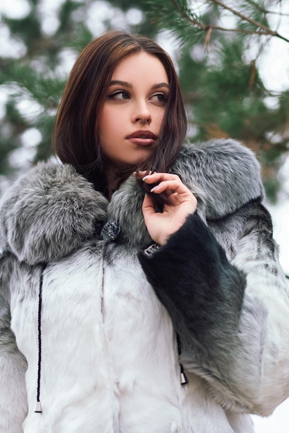 Moda mulher confiante posando fora da rua parque natureza inverno vestida com casaco de pele artificial