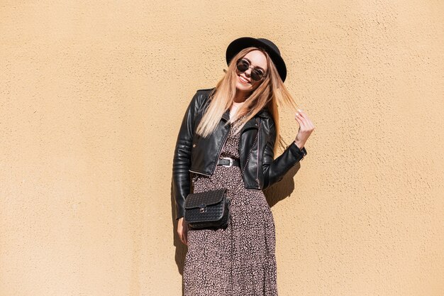 Moda mulher feliz com roupa da moda outono em uma jaqueta de couro elegante e vestido com bolsa pequena preta