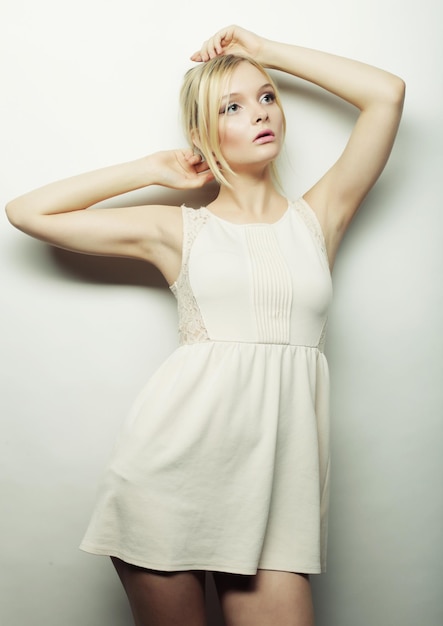 Moda mulher loira de vestido branco, posando no estúdio