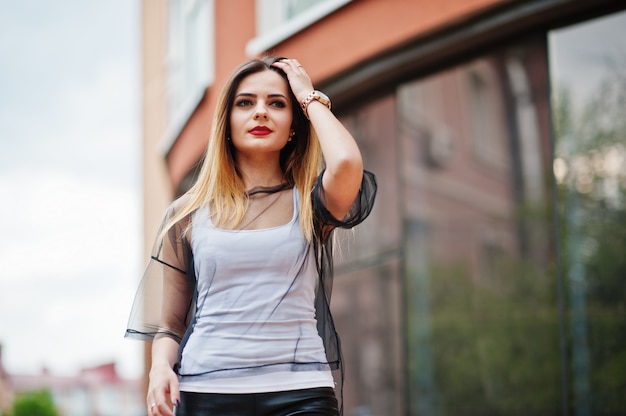 Moda mulher olha camisa branca, roupa transparente preta, calça de couro, posando na rua