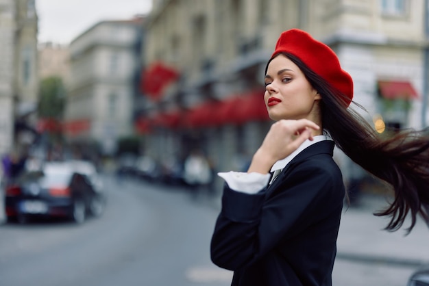 Foto moda mulher retrato beleza em pé na rua em frente à cidade em roupas elegantes com lábios vermelhos e boina vermelha viagens cor cinematográfica estilo retrô vintage moda urbana estilo de vida
