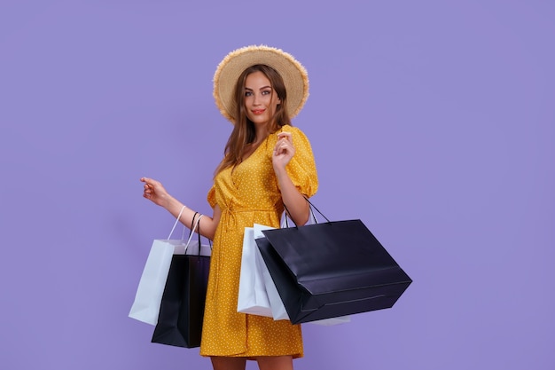 Moda mulher segurando sacolas de compras em fundo roxo.