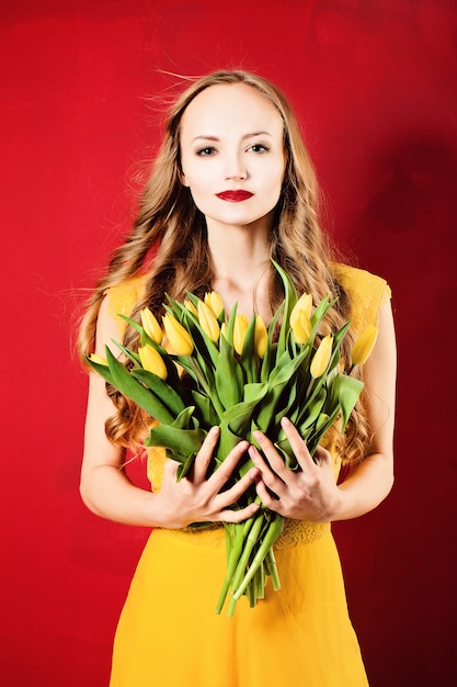 Moda mulher usando vestido amarelo em vermelho. Menina elegante com flores