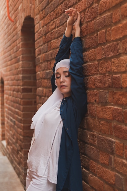 Moda de niña musulmana moderna con hijab.Hermosa modelo de mujer musulmana con hijab y ropa casual posando sobre fondo urbano