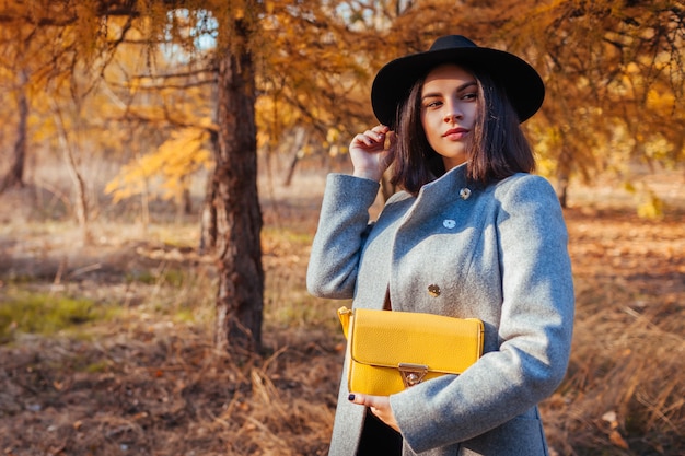 Moda outono. jovem mulher vestindo roupa elegante e segurando a bolsa ao ar livre