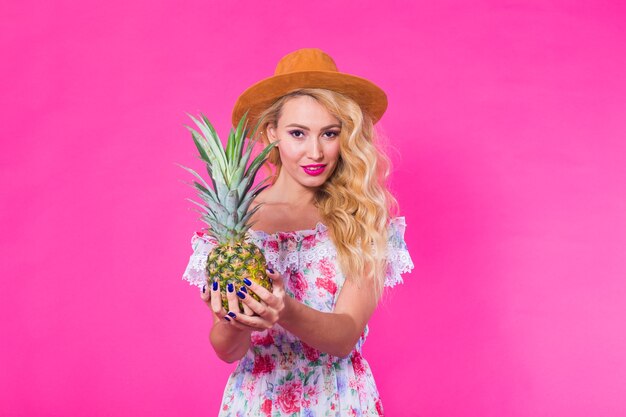 Moda retrato jovem mulher bonita com abacaxi sobre parede rosa.