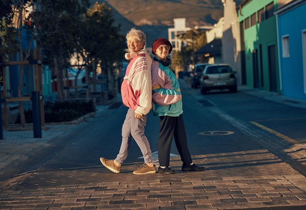 Moda urbana de mulher sênior e juntos na rua para amizade de retrato ou estilo ao ar livre Amigos de mulheres idosas e felizes na cidade com roupas retrô de tendência hip hop e sorriso ao sol no metrô