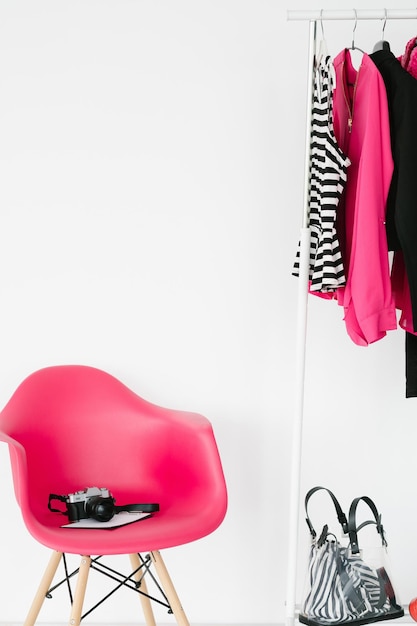 Mode-Blogger-Arbeitsbereich trendige bunte Kleidung, die an der Rack-Fotokamera auf dem Sessel hängt