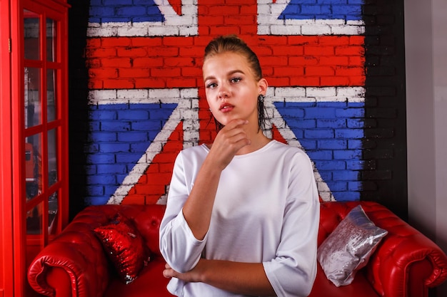 Mode glamouröses Porträt eines Mädchenmodells mit weißem Pullover auf Wandhintergrund mit britischer Flagge