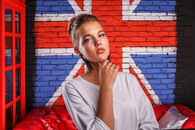 Mode glamouröses Porträt eines Mädchenmodells mit weißem Pullover auf Wandhintergrund mit britischer Flagge