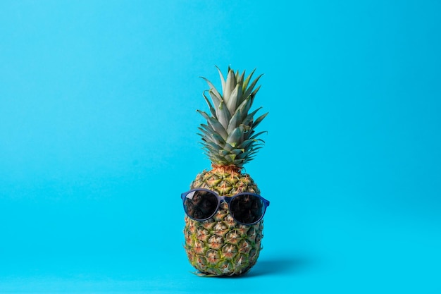 Mode-Hipster-Ananasfrucht mit Sonnenbrille auf blauem Hintergrund minimales Konzept